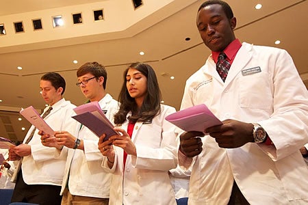From left, ECU medical students Eric Alspaugh, Daniel Allen, Syeda Ahmed and Adejare Adeleke recite an oath during the annual white coat ceremony for new students, held in August. Photo by Cliff Hollis