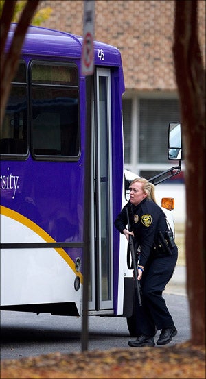 A police officer prepares to test the door on a bus parked at the Student Recreation Center on campus.