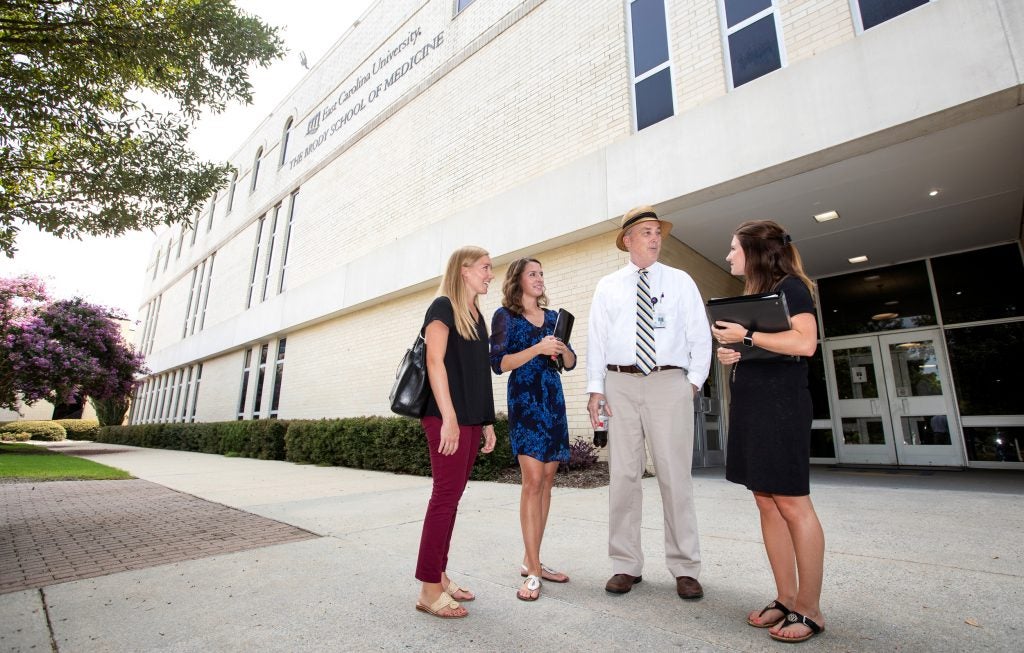 Dr. Robert Carroll speaks with students outside the Brody School of Medicine.