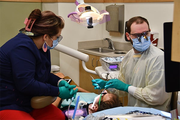 Two dental care providers in masks, gloves and gowns work on a patient using dental instruments during a special care event in Spruce Pine.
