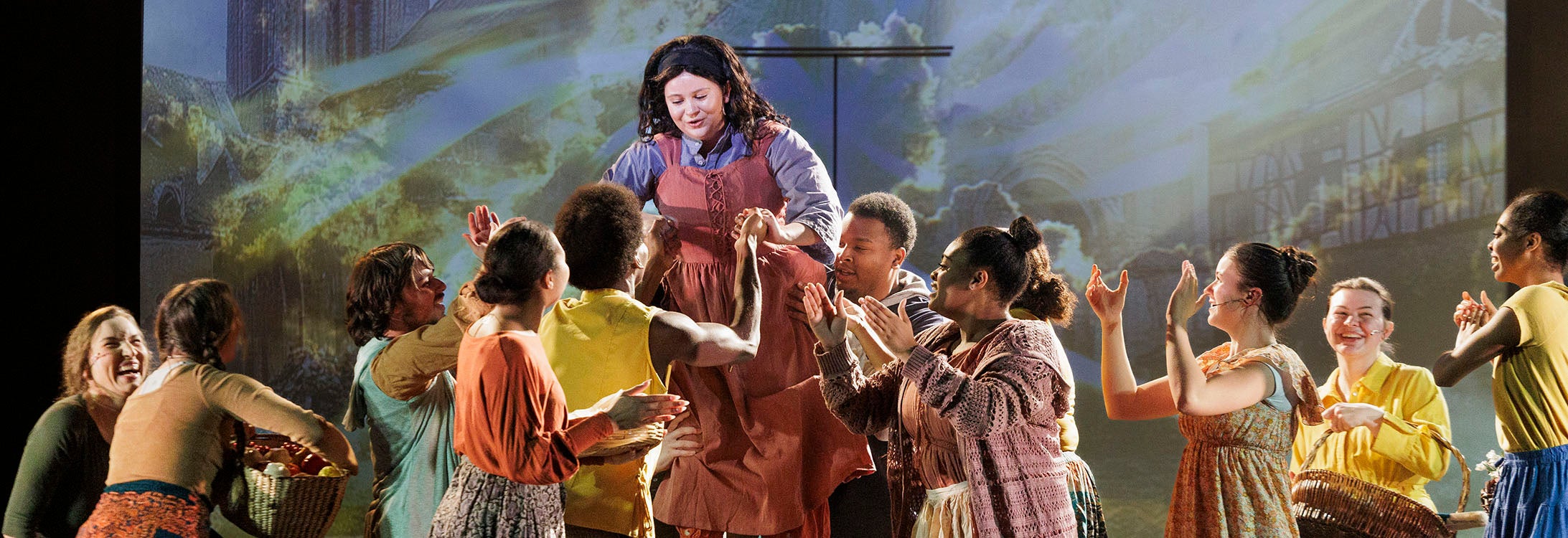 a group of young performers in French-inspired wardrobes sing on a large stage.