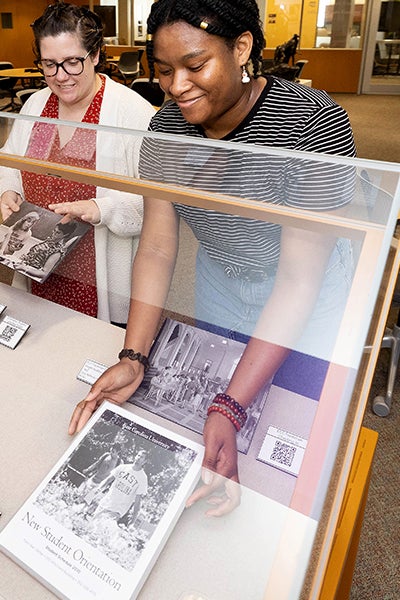 Student Shatiece Starks, right, smiles alongside Academic Library Services employee Kristen Daniel as they look at the new student orientation exhibit they curated.