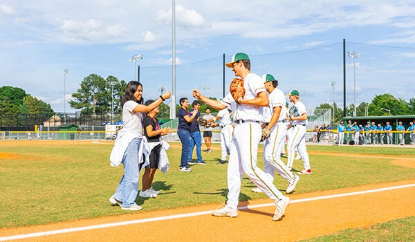 Greenville Yard Gnomes baseball players congratulate visitors from Peru after a ceremonial first pitch. (Contributed photo by Greenville Yard Gnomes)