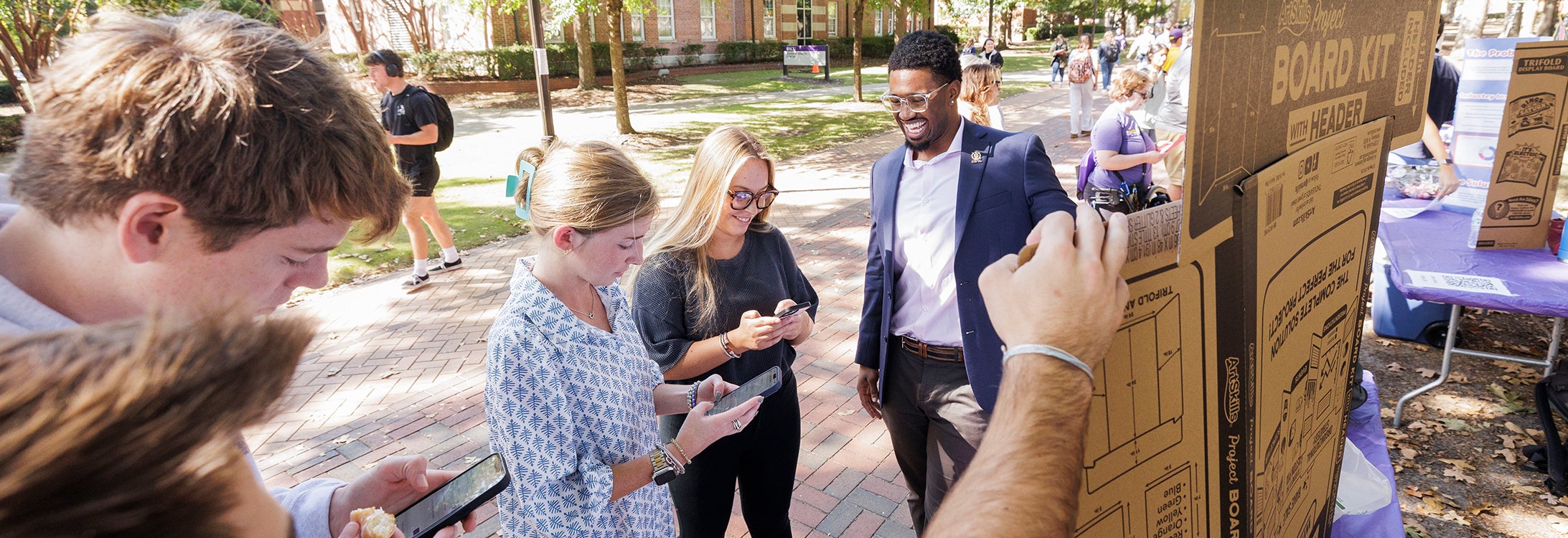 Challenge participant on ECU’s lawn speaks to two students about his entrepreneurial idea.