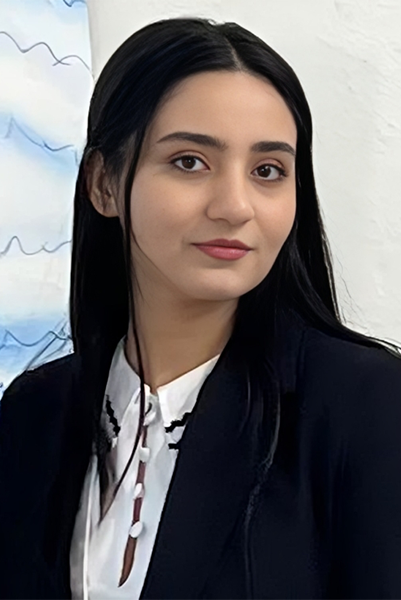 Mina Bikmohammadi has her head turned, and is wearing a white, button-down blouse and black jacket.