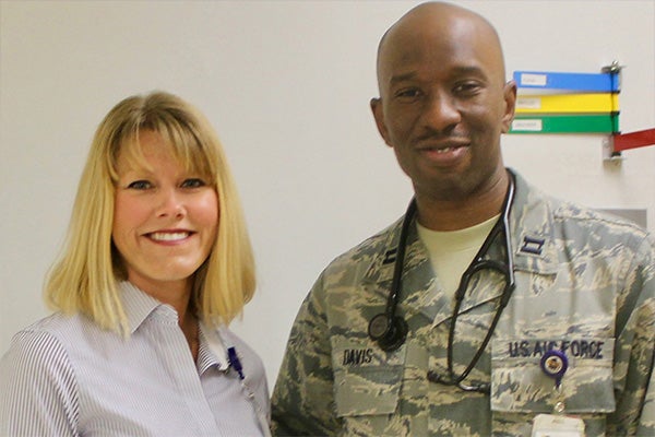 Angela Lamson stands and smiles with a military service member.