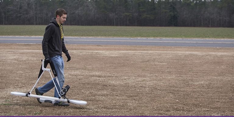 ECU geology graduate student Adam Trevisan heads to a research site carrying an electromagnetic induction profiler, used to trace water impurities so ECU researchers can follow where groundwater is flowing underground. The work is part of a collaborative effort to examine water contaminants that may migrate from home septic systems. (Photos by Cliff Hollis)