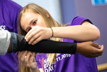 ECU student Kelsey Reeves puts a sleeve on a high school student during National Biomechanics Day.
