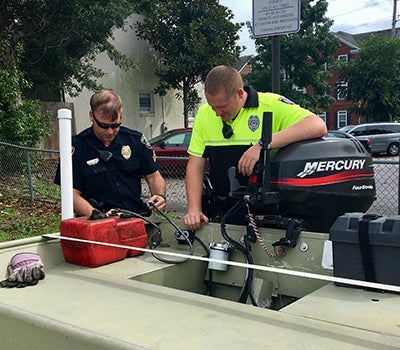 Sgt. Chester Jones, left, and Officer A. Ferguson of the ECU Police prepare a boat for possible rescue operations. (ECU Police Photo)