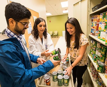 Dr. Susan Keen collects and weighs food for the food pantry at ECU’s Brody School of Medicine with M3 students Shazeb Khan and Shannon Osborne.
