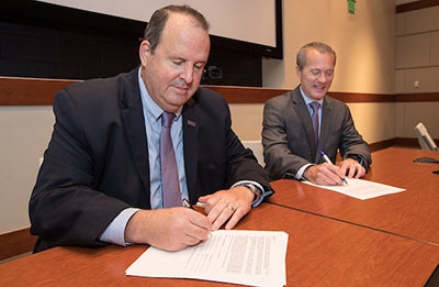 Jay Golden, left, ECU vice chancellor of research, economic development and engagement signs a memorandum of understanding with Shannon Lasater, senior consulting manager of SAS Education Practice, at the East Carolina Heart Institute on Nov. 2. (Photo by Rhett Butler)