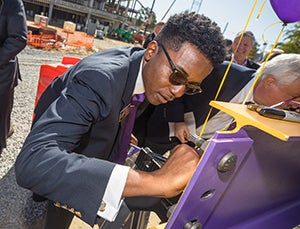 La’Quon Rogers, ECU SGA president, signs the final beam in the student center construction project.