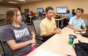 Instructor works with two Summer Innovation Academy attendees