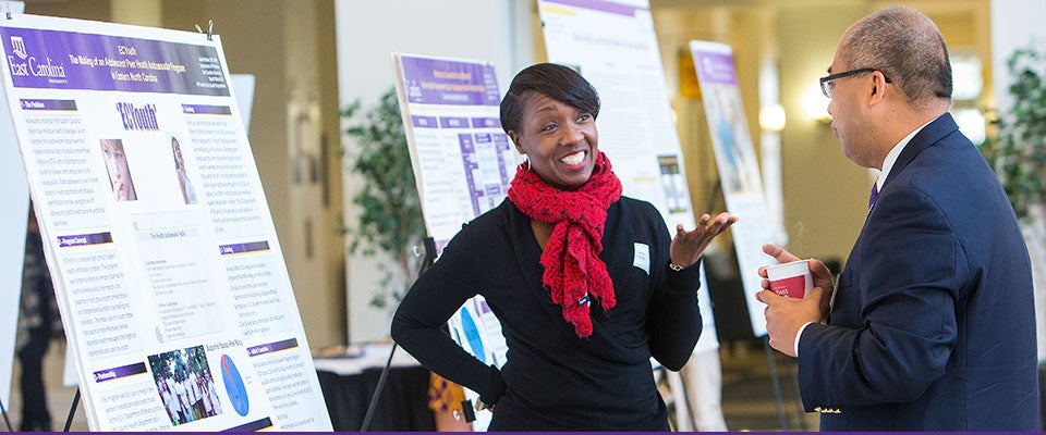 Vashti Kitrell from the Pitt Co. Health Department discusses a display in the lobby of the ECHI with ECU's Xiaoming Zeng during the Mills Symposium. (Photos by Jay Clark)