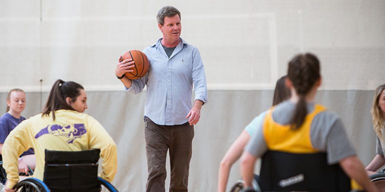 Dr. Richard Williams teaches students from his recreational therapy class to play wheelchair basketball in the student recreation center.