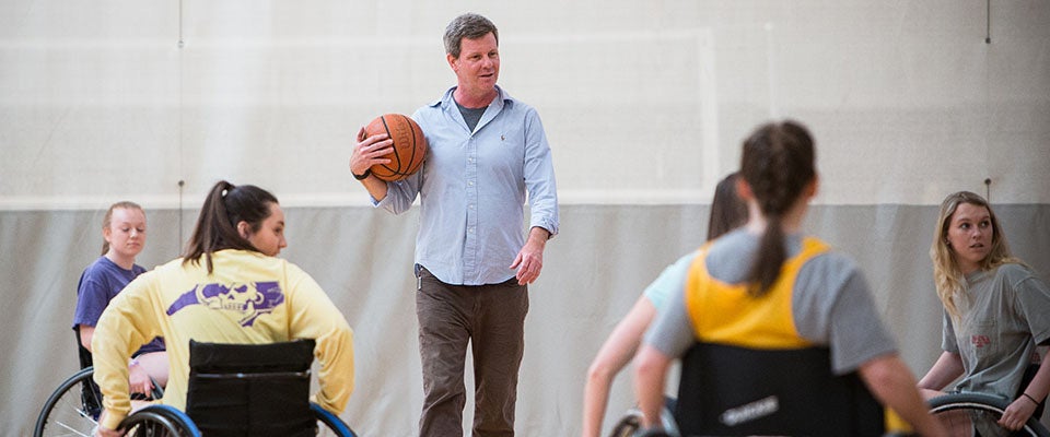 Dr. Richard Williams teaches students from his recreational therapy class to play wheelchair basketball in the student recreation center.