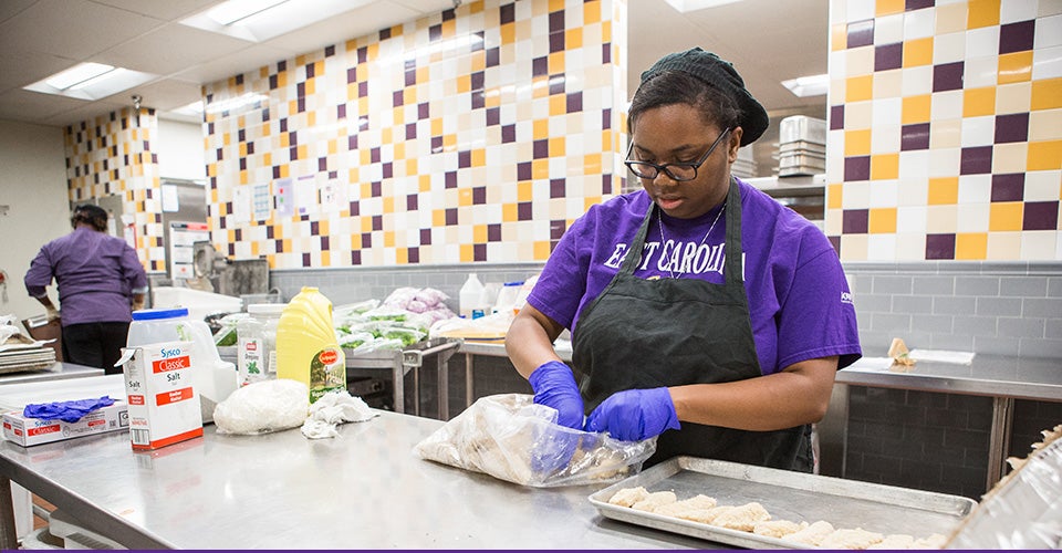 ECU senior and Campus Kitchens shift leader Lekisha Pittman of High Point prepares chicken tenders at Todd Dining Hall. The chicken tenders along with green beans and fruit were being prepared for community partner Operation Sunshine. (Photos by Cliff Hollis)