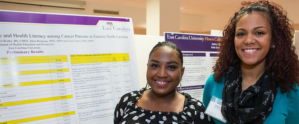 Chelsey Turner, left, and Cheyenna Francis pose with their poster detailing their research into medication adherence and health literacy among cancer patients. (Photos by Cliff Hollis; videos by Rich Klindworth)