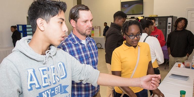 ECU student Casey Nolan listens to Maximillian Galvan Rojas, age 14, and Rachel Garrett, age 12 speak about their science project. Both students attend Ayden Middle School. (Photos by Jay Clark)