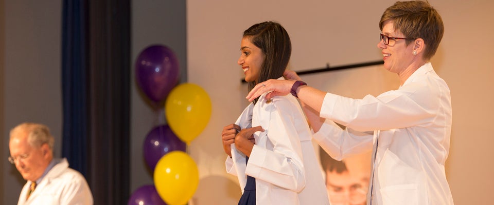 Associate Dean for Student Affairs Susan Schmidt helps incoming medical student Noopur Doshi into her white coat during Friday’s ceremony at the Brody School of Medicine. (Photos by Gretchen Baugh)