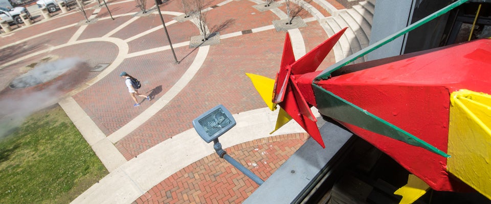 A brightly colored cuckoo emerges from the Sonic clock tower during a test run of the installation in the plaza next to Joyner Library. (Photos by Cliff Hollis)