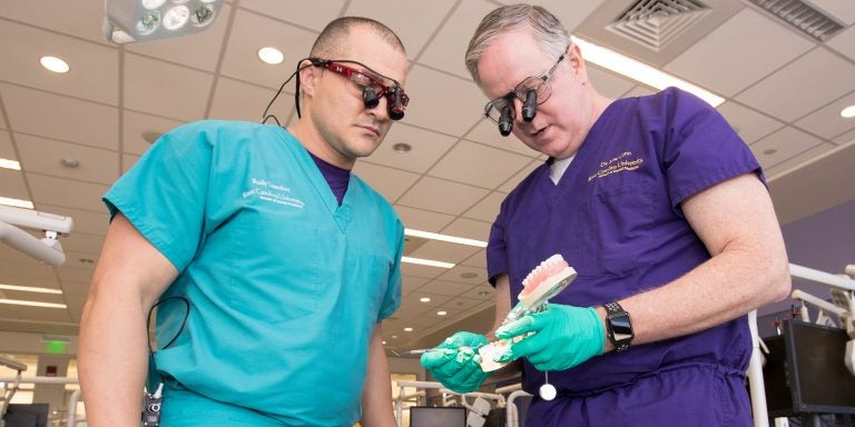 Dr. Linc Conn (right) inspects the work of first-year dental student Rudy Oxendine. Oxendine is a former Greenville police officer. (Photo by Rhett Butler)