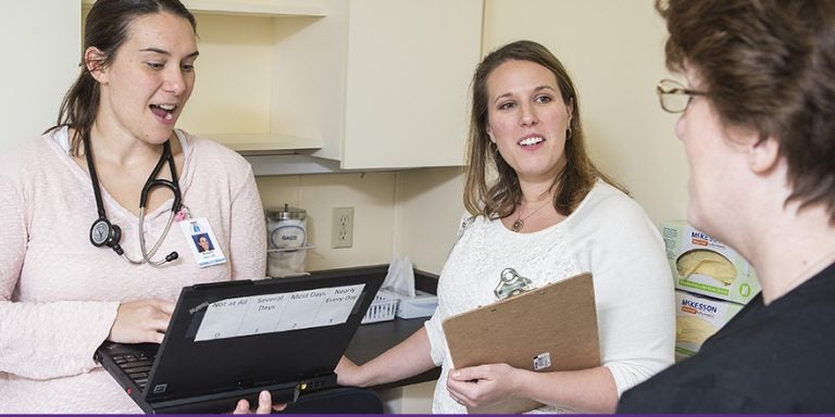 Dr. Modjulie Moore, left, and Julie Austen collaborate to assist a patient. Austen is among the 2014 graduates of the Health Psychology doctoral degree with a concentration in pediatric school psychology. (Photo by Cliff Hollis)