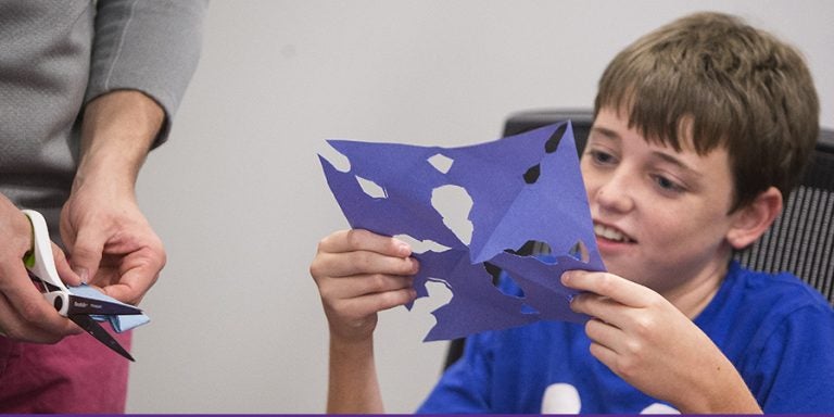 Nick Dixon examines artwork he created with help from ECU student participants in the Eye to Eye afterschool mentoring program, which pairs college students with learning disabilities with local students who share the same obstacles. ECU's chapter of the nationwide program will benefit from a grant from William R. Kenan Jr. Charitable Trust. (Photos by Cliff Hollis)