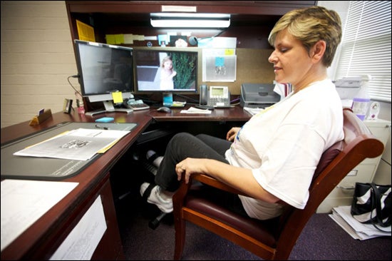 Joy Hahn, administrative support associate in the Department of Exercise and Sport Science at ECU, tries out a new mini exercise bike that allows users to pedal while sitting at a desk. The bikes are part of an ECU research program on ways to offset the negative effects of sedentary work. (Photo by Cliff Hollis)