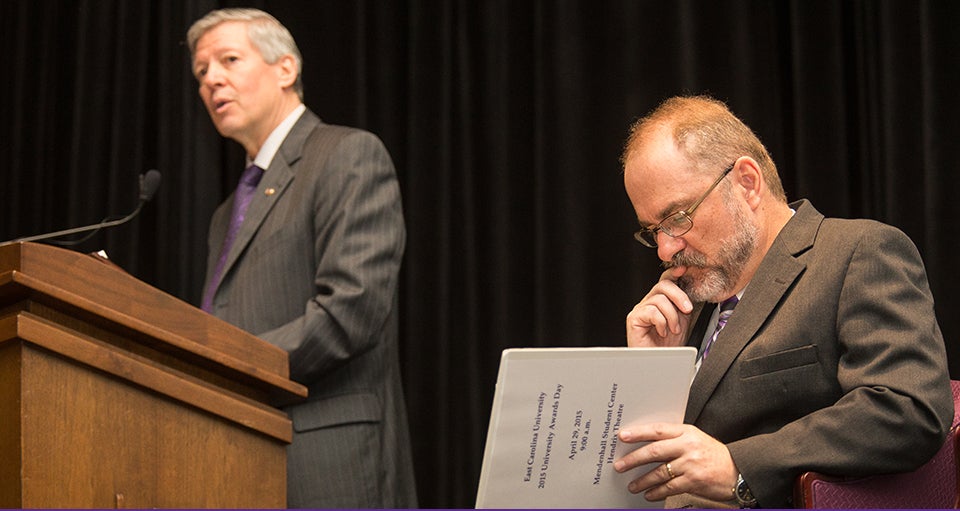 ECU Chancellor Steve Ballard speaks during the university's awards day ceremonies, while Provost Ron Mitchelson studies the order of events. (Photos by Cliff Hollis)