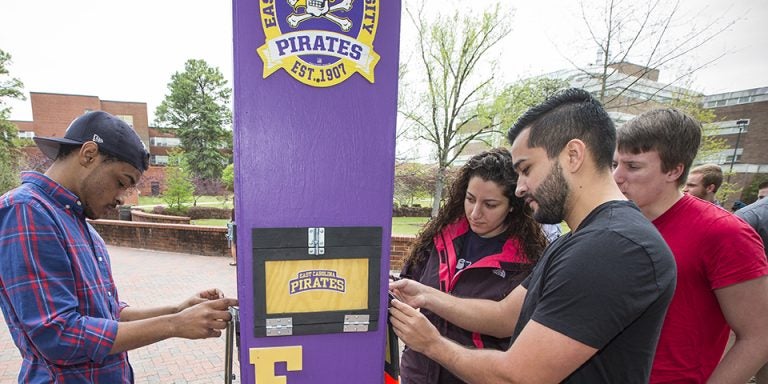 Left to right, student Vaughn Logan, Sandy Jalal, Jesus Lucena and Cass Palombaro put the finishing touches on a solar charging station they created for an industrial engineering technology class at East Carolina University. (Photos by Cliff Hollis)