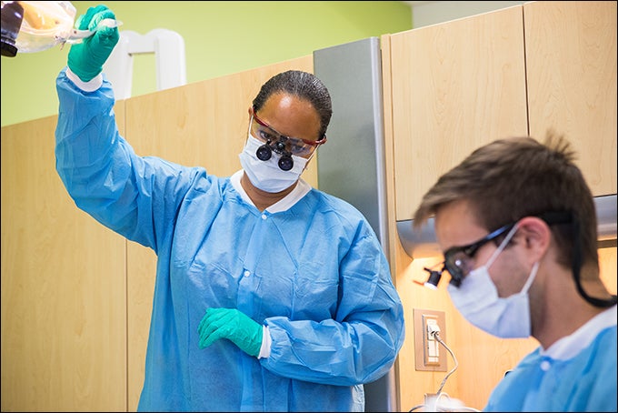 ECU School of Dental Medicine professor Dr. Kimberley Gise, left, and Zachary Swanner, fourth year dental student, assist a dental patient. Gise is director of the emergency care clinic. (Photo by Cliff Hollis)