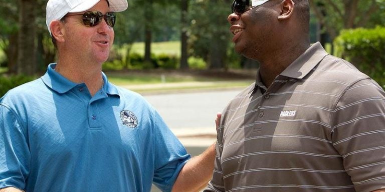 Former head football coach Skip Holtz, left, and former player C.J. Wilson, now in the NFL, talk at the tournament. Photo by Cliff Hollis, ECU News Services.