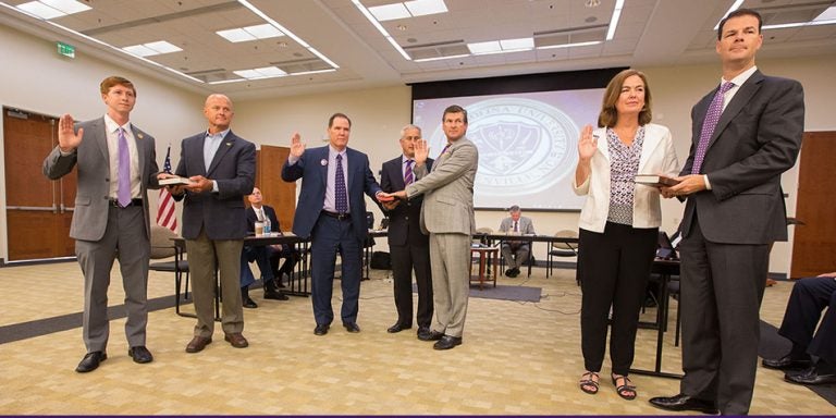 Pictured above at the swearing-in ceremony for the ECU Board of Trustees are, left to right, ECU Student Government Association president Mark Matulewicz with his father, Stephen; Kieran Shanahan and Kel Normann with Steve Jones shown between them holding the Bible; and Leigh J. Fanning and her husband, Paul. (Photos by Cliff Hollis)