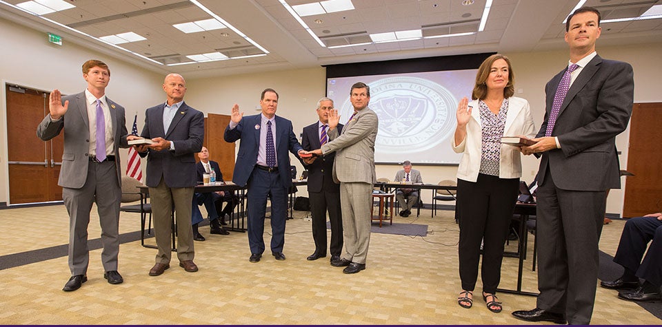 Pictured above at the swearing-in ceremony for the ECU Board of Trustees are, left to right, ECU Student Government Association president Mark Matulewicz with his father, Stephen; Kieran Shanahan and Kel Normann with Steve Jones shown between them holding the Bible; and Leigh J. Fanning and her husband, Paul. (Photos by Cliff Hollis)