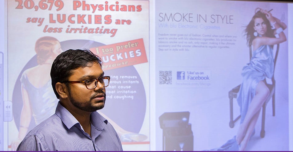 ECU professor Dr. Vivek Anand has completed research that demonstrates a large number of teens in eastern North Carolina are using e-cigarettes, with minimal knowledge of associated health hazards. Anand is pictured above with a sample of e-cigarette advertising, at right, compared with tobacco advertising from years past. (Photo by Jay Clark)