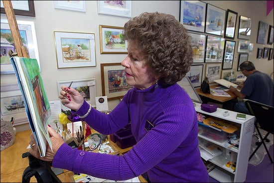 East Carolina University nursing professor Lou Everett paints an original watercolor as Pete Hickey works in the background at the Painting Purple & Other Colors Artists' Working Studio and Gallery, 4320-G East 10th Street, Greenville. Hickey and the Groessers will open the shop for the first artist studio tour on Nov. 5 to raise funds for scholarships in the ECU School of Art and Design. (Photos by Cliff Hollis)