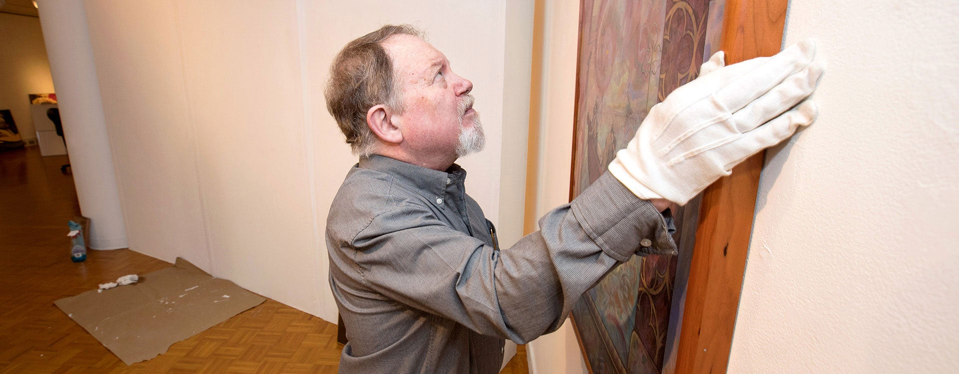 Tom Braswell, interim director of the Wellington B. Gray Gallery, hangs a piece of art in a new exhibit opening May 23. (Photos by Rhett Butler)