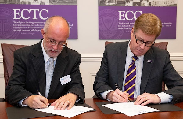 Dr. Robert Wynegar, president of College of the Albemarle, signs a co-admission agreement alongside ECU Chancellor Cecil Staton.
