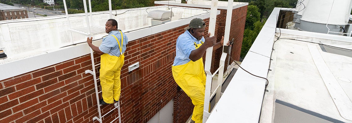 Milbert Moore, left, and Monuel Purnell look for damage on the rooftop of the Science and Technology Building. (ECU Photo by Cliff Hollis)