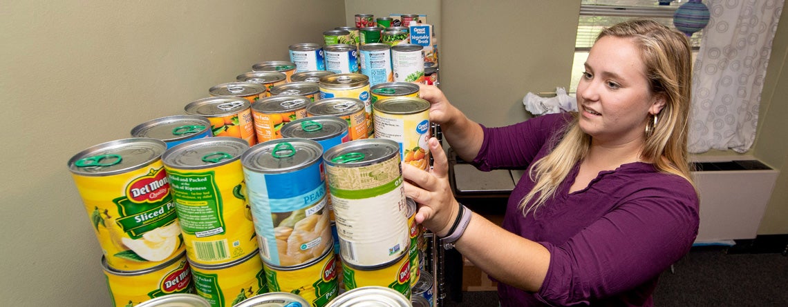 Ashton Fisher stocks the shelves at the Purple Pantry with canned goods.
