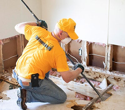 Michael Van Scott, Senior Associate Vice Chancellor for Research, Economic Development and Engagement, pulls up floor boards at the home of New Bern resident Byun Serchom. Scott was part of an ECU volunteer team that helped remove debris from storm-damaged homes.