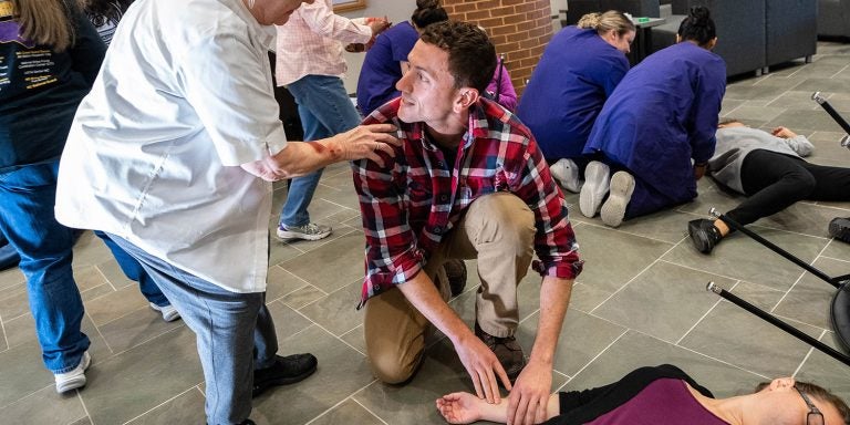 Brody School of Medicine student Dylan Flood pauses to speak to a victim while assessing another during the interprofessional mass casualty simulation at the College of Nursing on Nov. 10. (Photos by Cliff Hollis)