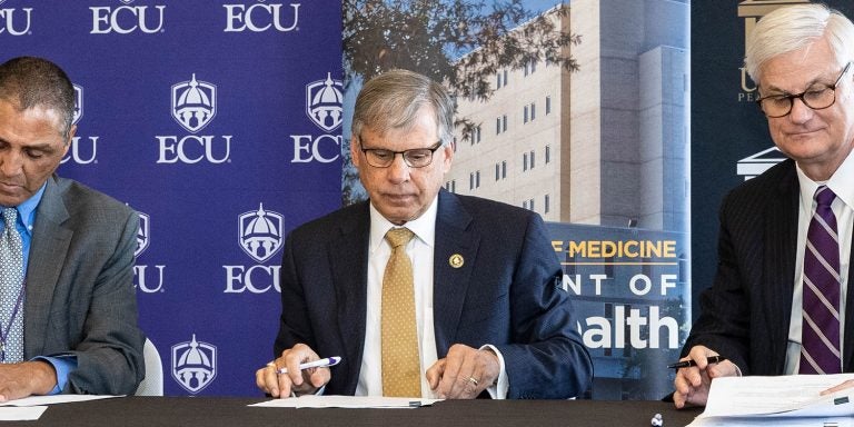 (From left) Dr. Ronny Bell, chair of ECU’s Department of Public Health, UNC-Pembroke Chancellor Dr. Robin Gary Cummings and Dr. Mark Stacy, dean of ECU’s Brody School of Medicine, sign a memorandum of understanding on Dec. 6, 2018 to formalize a public health partnership between the two schools. (Photo by Cliff Hollis)