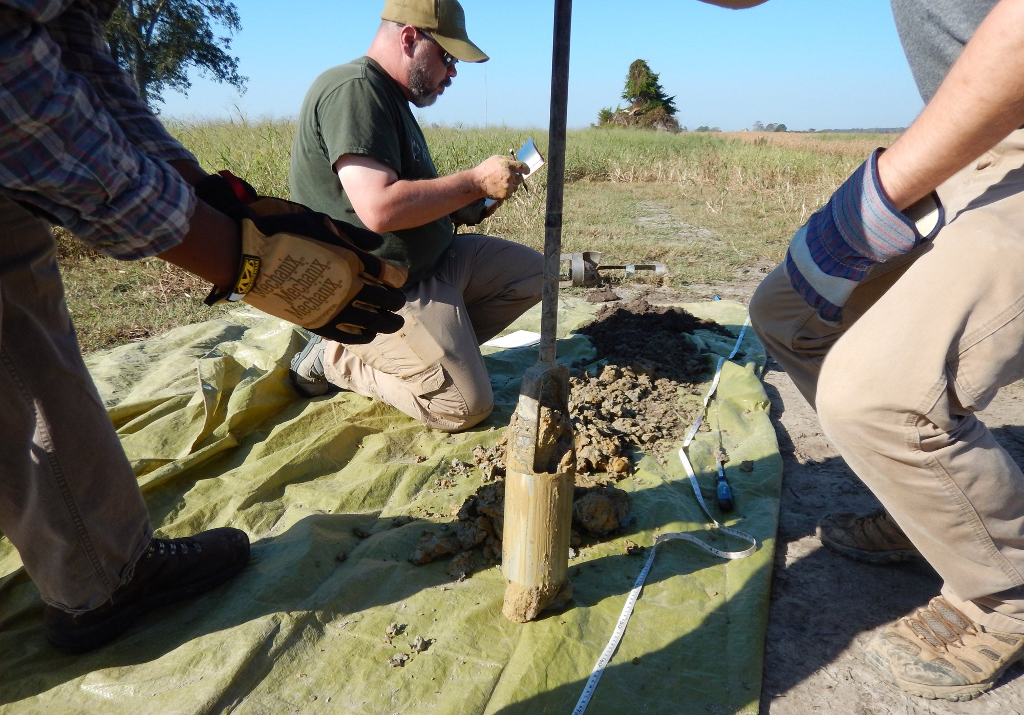 Graduate student Kyle Prock (left) and Manda extract a soil sample from a field in Hyde County.