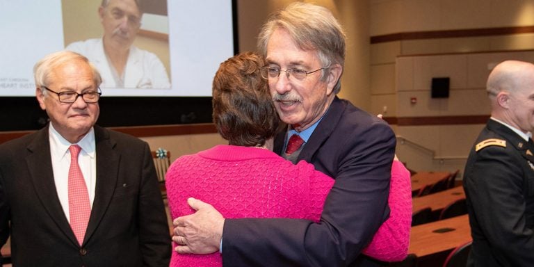 Dr. Mark Williams shares a hug with a friend after a ceremony for the establishment of the Travis and Cassandra Burt Professorship in Cardiovascular Sciences at the ECHI, as Dr. Randolph Chitwood, left, the founder and former head of ECHI, looks on. (Photos by Rhett Butler)