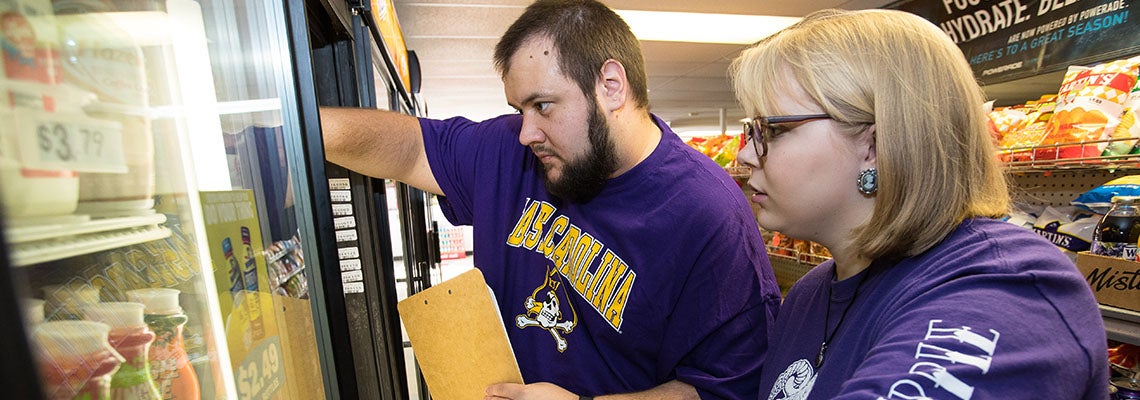 ECU graduate students Taras Grinchak, left, and Cami Howell conduct a food survey at Mark’s Food Mart in Greenville in 2017.