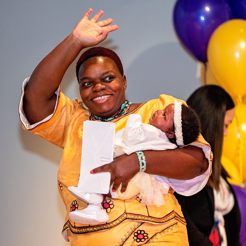 Consola Esambe Lobwede crosses the stage with her 5-week-old daughter, Charlotte, during the Brody School of Medicine’s 2019 Match Day event.