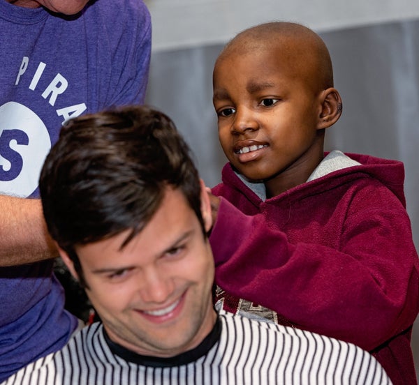 •A patient helps shave the head of first-year medical student Ross Masters.