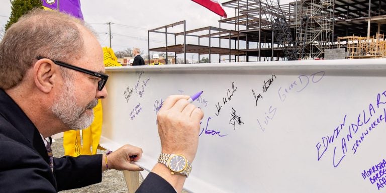 Interim Chancellor Dr. Ron Mitchelson signs the final beam that was placed as part of construction of the new Life Sciences and Biotechnology Building on Wednesday. The placement of the final beam, known as topping out, signifies a milestone in construction of the building that is scheduled to open in August of 2021.<br>(Photos by Cliff Hollis)
